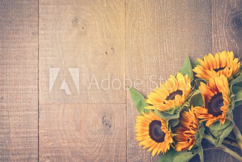 Fototapeta Autumn background with sunflowers on wooden table. View from above. Retro filter effect