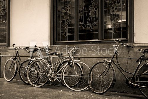 Fototapeta Bicycles leaning against old wall in sepia
