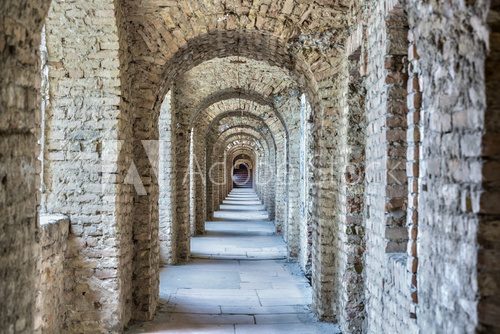 Fototapeta Castle tunnel with a series of arches in the ruined Bastion fortress in the Slovak city of Komarno.
