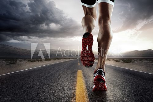 Fototapeta Sports background. Runner feet running on road closeup on shoe.