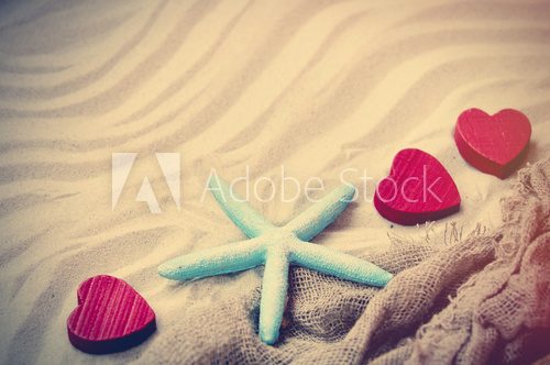 Fototapeta starfish, hearts and fishnet on the sand