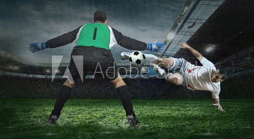 Fototapeta Two football players in action under rain in stadium