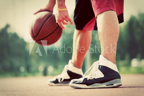 Fototapeta Young man on basketball court dribbling with bal