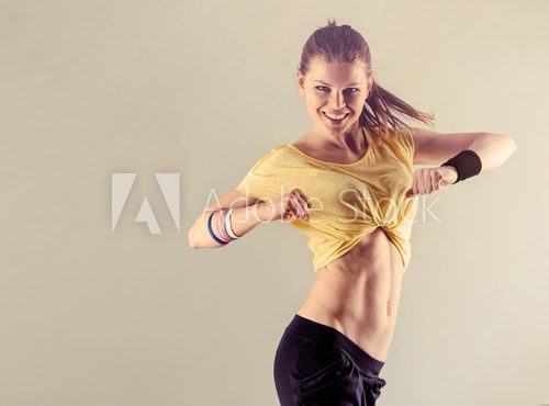 Fototapeta Aerobics fitness workout. Young athletic female dancing street dance in studio.  Concept of sport and health. 