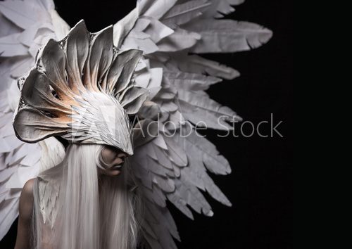 Fototapeta Angel, costume, concept, cinematic, a portrait of a young girl and a white wig , which carries a large white mask and a large white wings. Dramatic