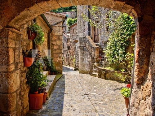 Fototapeta Arched cobblestone street in a Tuscan village, Italy