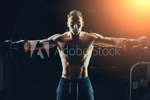 Fototapeta Athlete muscular bodybuilder training back with dumbbell  in the