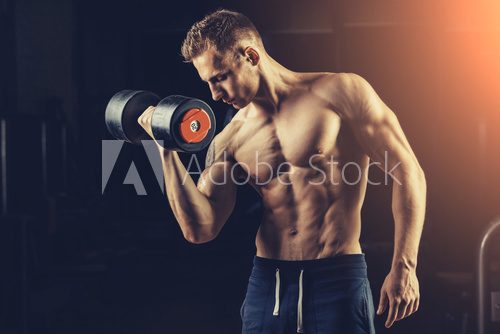 Fototapeta Athlete muscular bodybuilder training back with dumbbell  in the