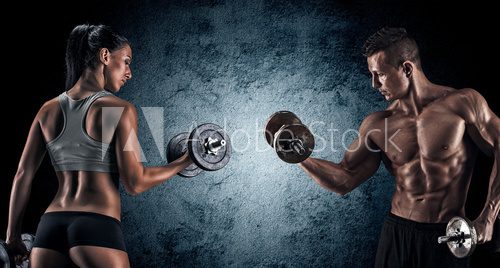 Fototapeta Athletic man and woman with a dumbells.