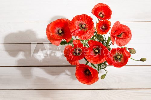 Fototapeta Bouquet of red poppies in glass vase on old white wooden table