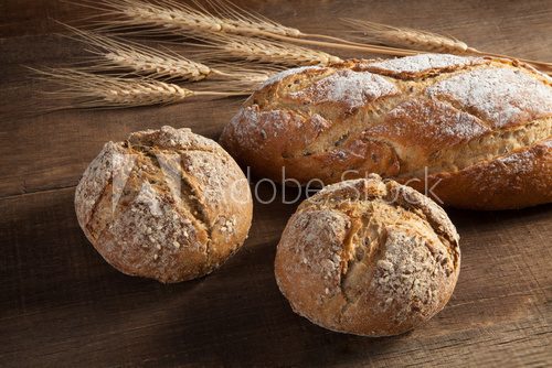 Fototapeta Bread and wheat ears on wooden background