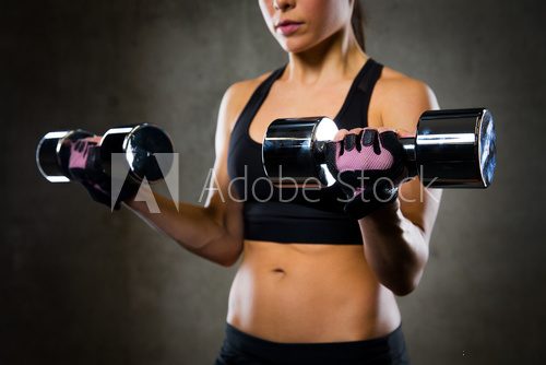 Fototapeta close up of woman flexing arms with dumbbells