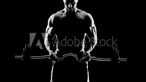 Fototapeta Close up of young muscular man lifting weights over dark backgro