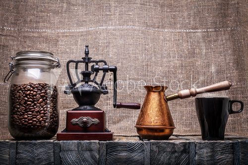 Fototapeta Coffee beans in a glass jar, coffee grinder, a coffee pot, a mug