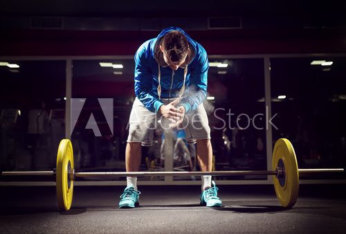 Fototapeta Cross fit weightlifter preparing for training. Shallow depth of field, selective focus on hands and dust.