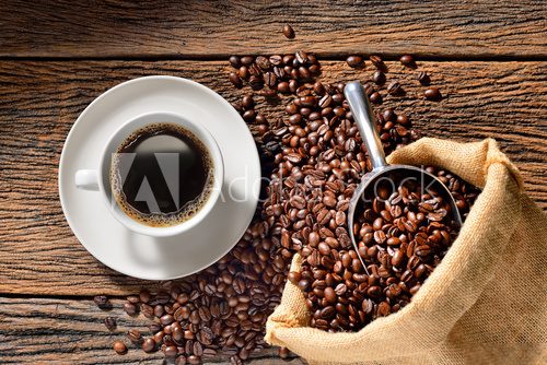 Fototapeta Cup of coffee and coffee beans on old wooden table