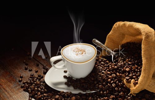 Fototapeta Cup of coffee with smoke and coffee beans on old wooden table