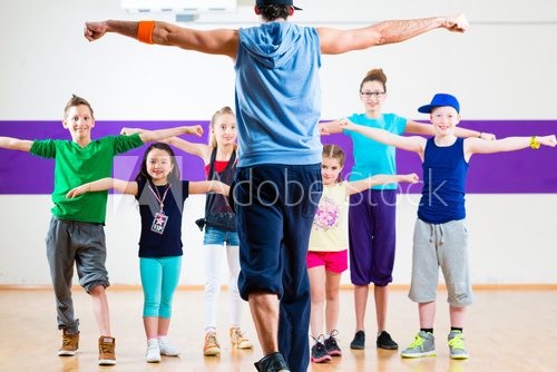 Fototapeta Dance teacher giving kids Zumba fitness class