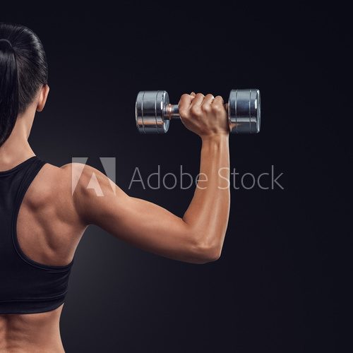 Fototapeta Fitness woman in training muscles of the back with dumbbells