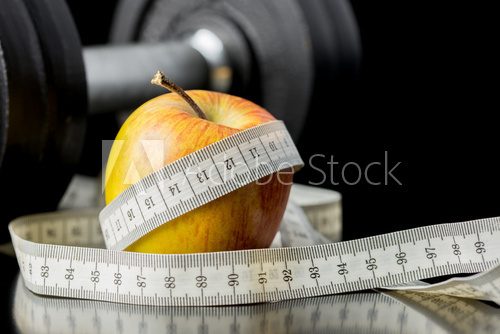 Fototapeta Fresh juicy apple wrapped in a tape measure