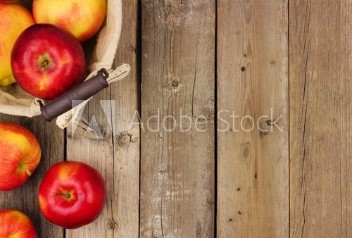Fototapeta Freshly harvested apples with basket, side border on a rustic aged wood background