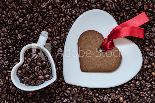Fototapeta Heart shaped cup and cookie on coffee beans background