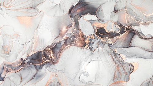 Fototapeta Luxury abstract fluid art painting in alcohol ink technique, mixture of black, gray and gold paints. Imitation of marble stone cut, glowing golden veins. Tender and dreamy design.