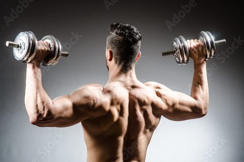 Fototapeta Muscular ripped bodybuilder with dumbbells