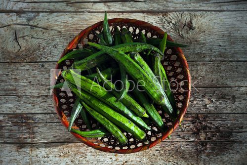 Fototapeta Okra or bhindi, bamia vegetable in a basket on wood background