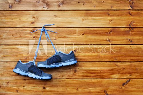 Fototapeta pair of sport shoes hang on a nail on a brown wooden wall