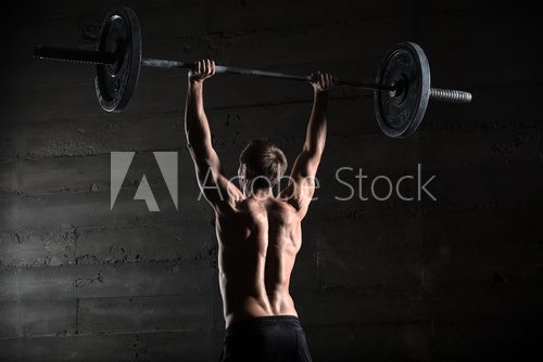 Fototapeta Portrait of a handsome athlete from behind. Athlete raises the b