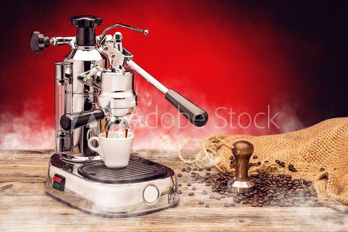 Fototapeta professional manual silver coffee machine with cup of coffee, stamper and sack coffee beans on red background, product protography for coffee shop