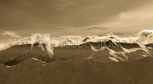 Fototapeta Sepia winter mountains at evening and sunlight clouds