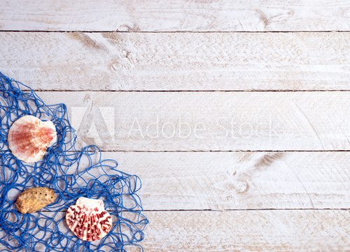 Fototapeta Shells and blue fishing net on wooden background