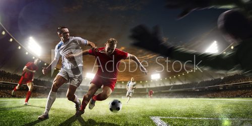 Fototapeta Soccer players in action on sunset stadium background panorama