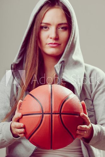 Fototapeta Sporty teen girl in hood holding basketball.