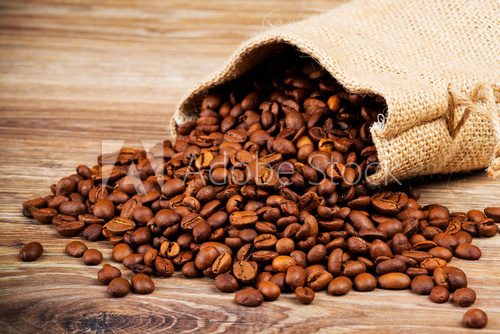 Fototapeta The sack of coffee beans on wooden background