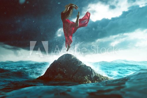 Fototapeta Woman dances on a rock in the sea