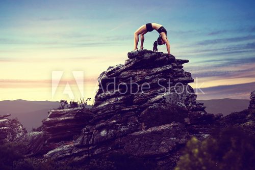 Fototapeta Woman does gymnastics on a rock