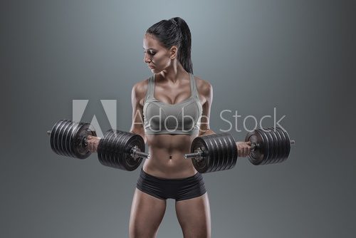 Fototapeta Young woman lifting the dumbbells